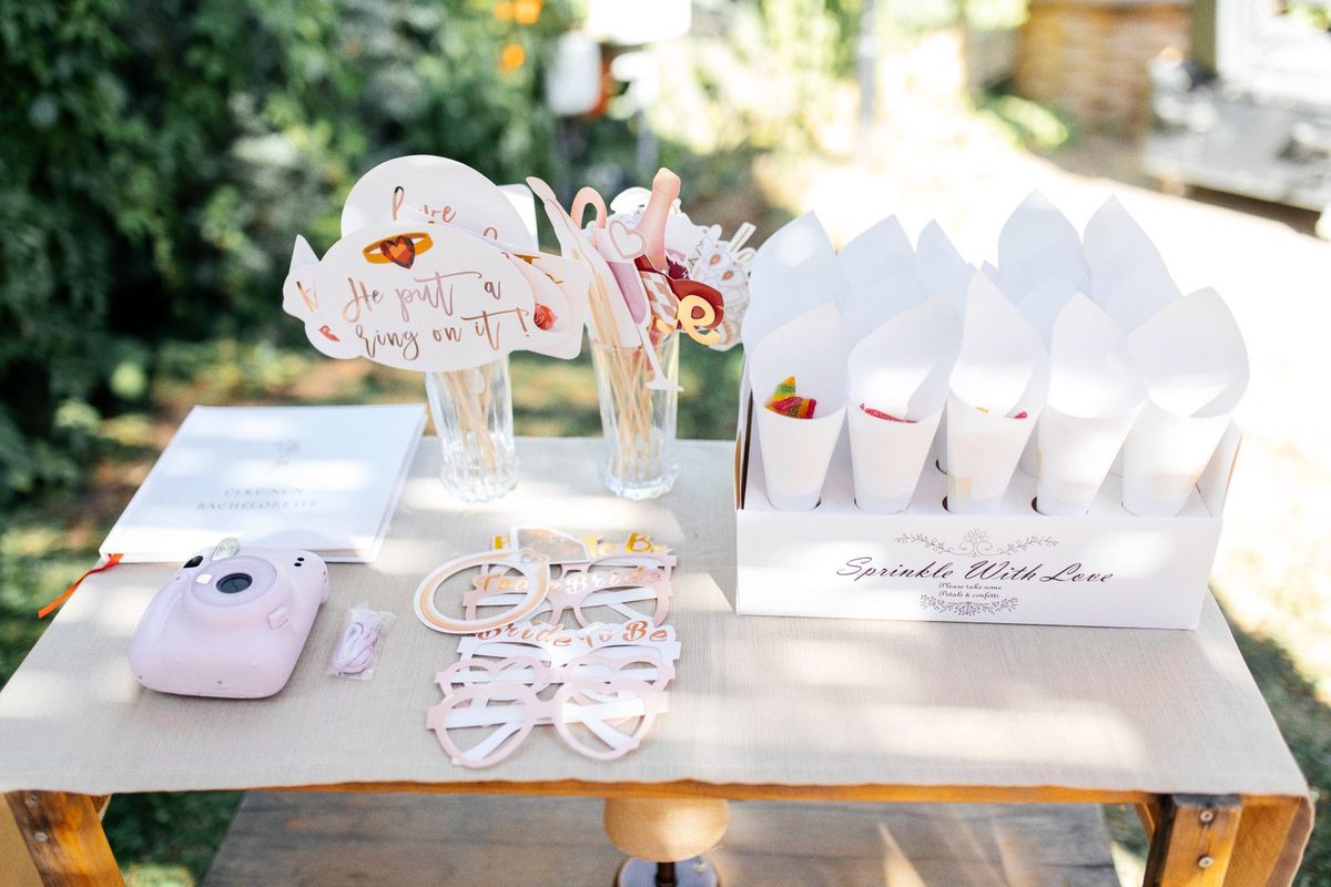 Outdoor party table with an instant camera, heart-shaped sunglasses and printed photos