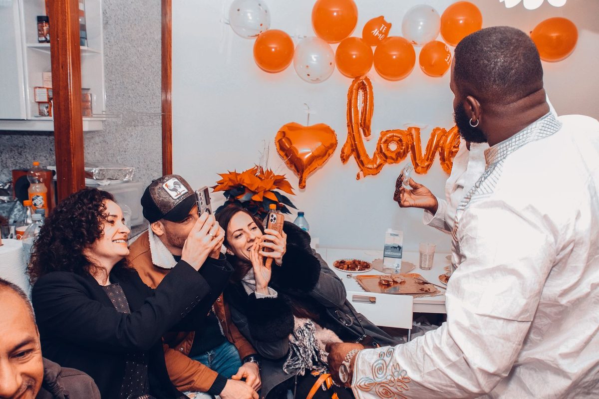 Friends with phones and balloons cheering at an indoor party
